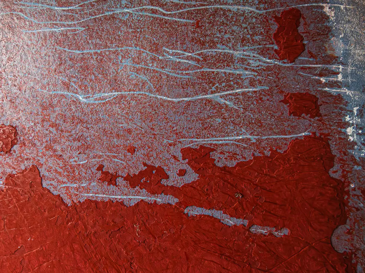 Patterns of rust and barnacles on the hull of a boat out of water.