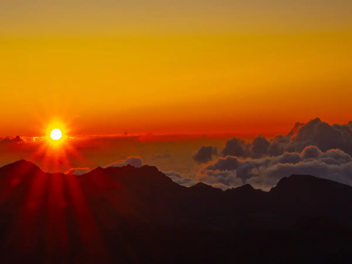 Above the clouds during sunrise on the top of Haleakala volcano in Hawaii with the sun coming up