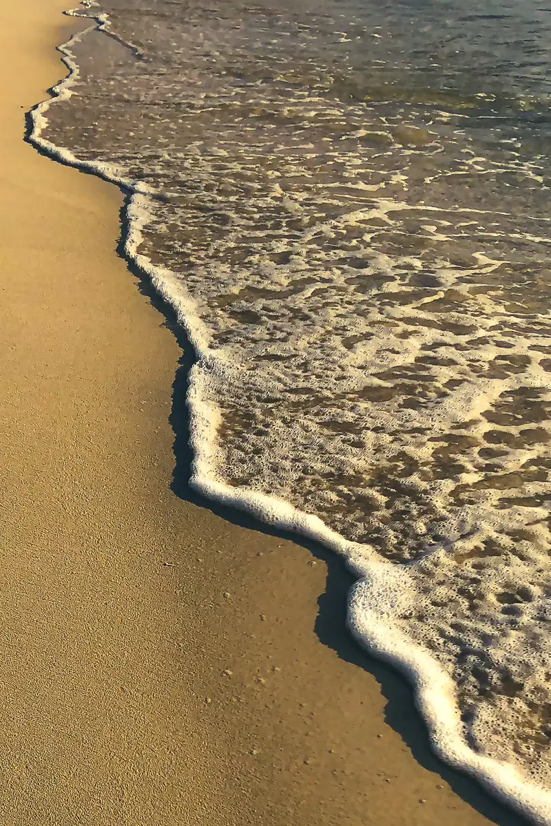smooth beach showing an abstract line of foam at the waters edge