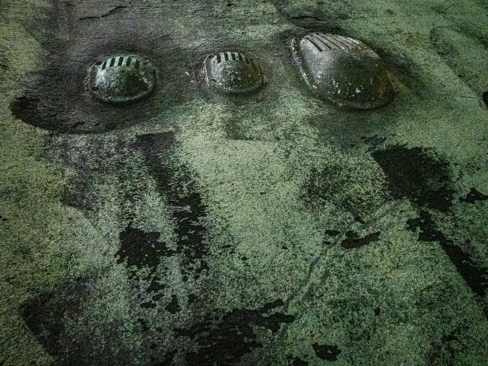 Patterns of rust and barnacles on the hull of a boat out of water.