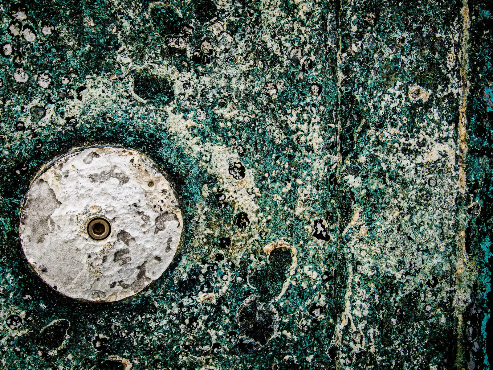 Patterns of rust and barnacles on the hull of a boat out of water.