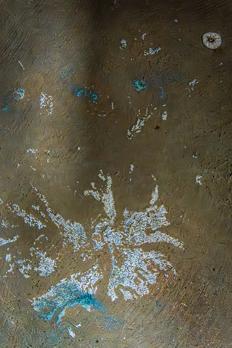 Patterns of rust and barnacles on the hull of a boat out of water.