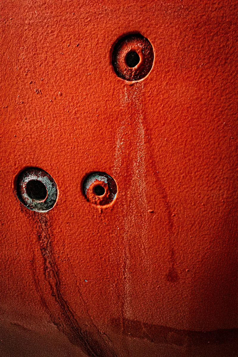 Patterns of rust and barnacles on the hull of a boat out of water.