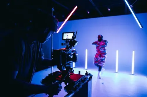 Cameraman filming a person dancing in a studio with blue and red neon lights.