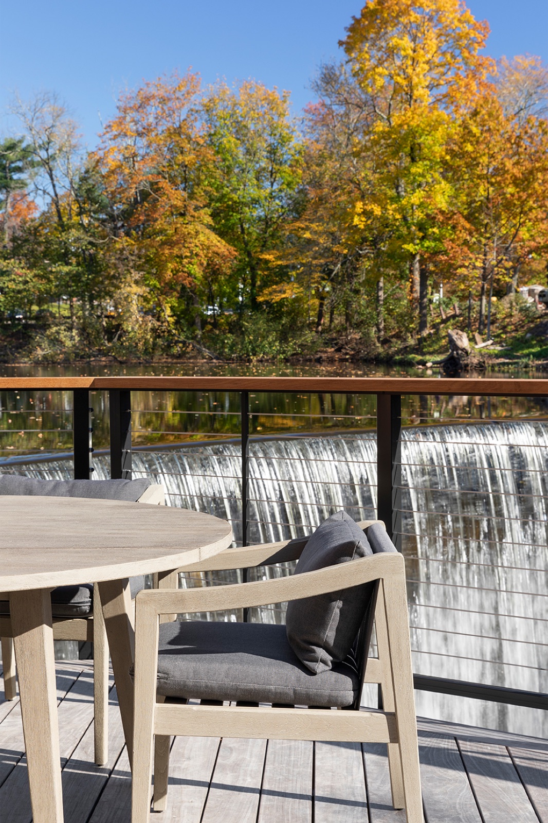 Outdoor dining deck overlooking a waterfall and autumn trees