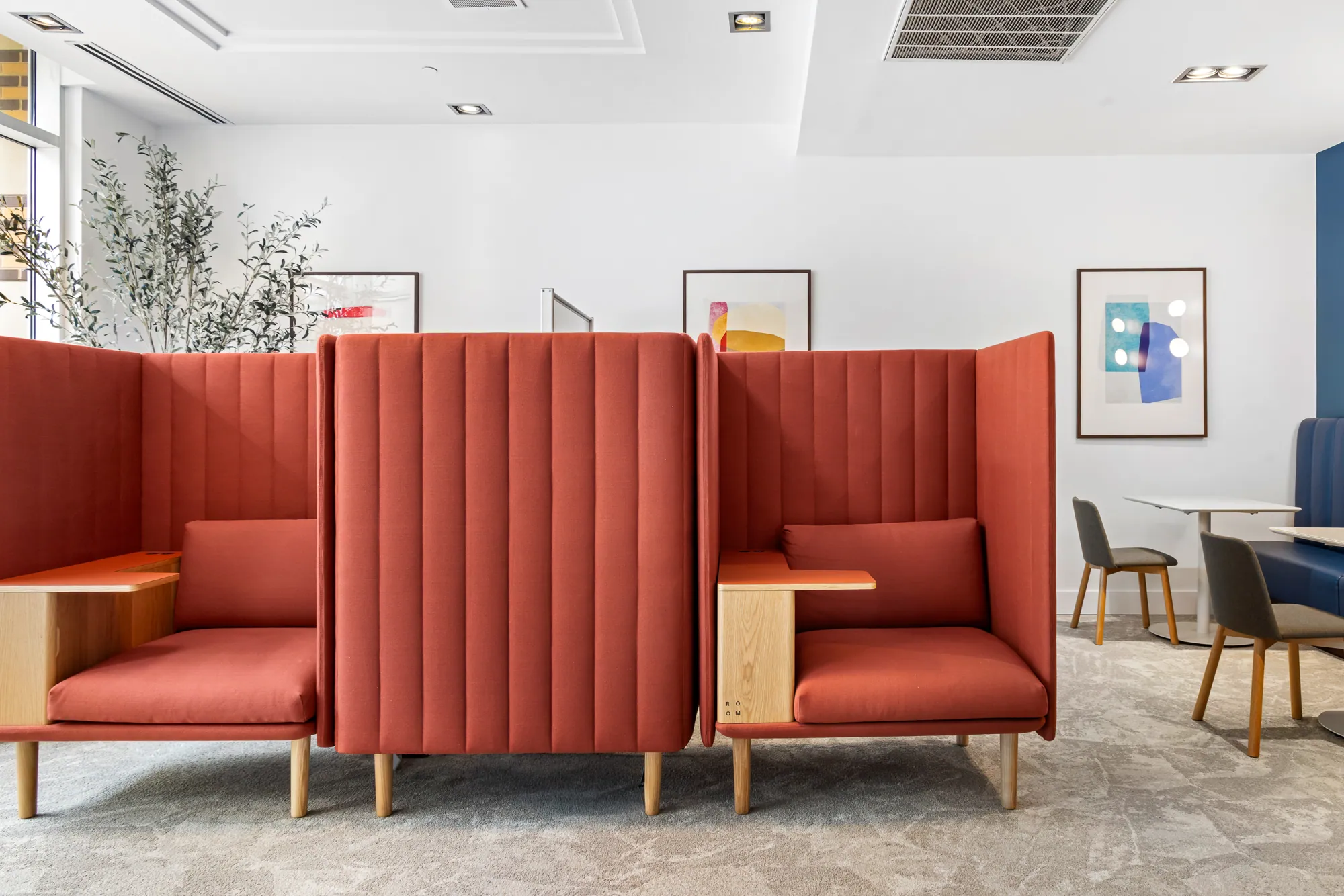 Coral upholstered booths in a bright co-working lounge