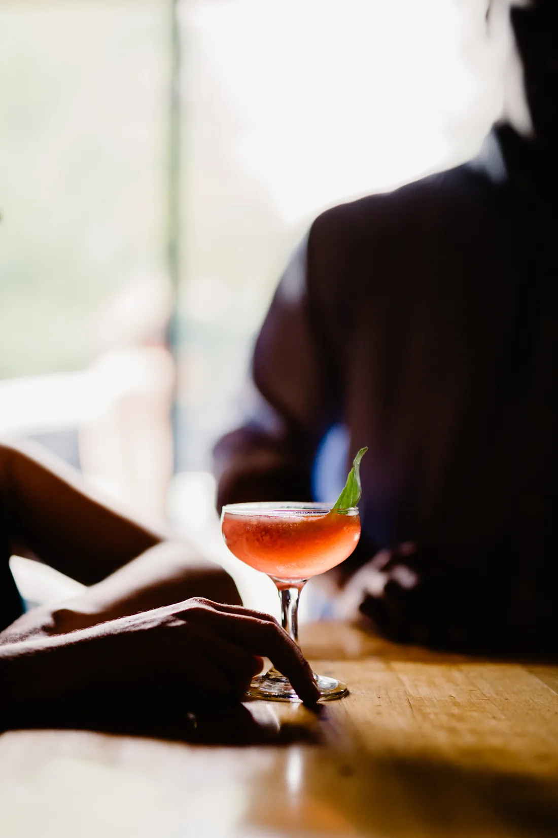 Coral cocktail on a wooden bar in warm backlight