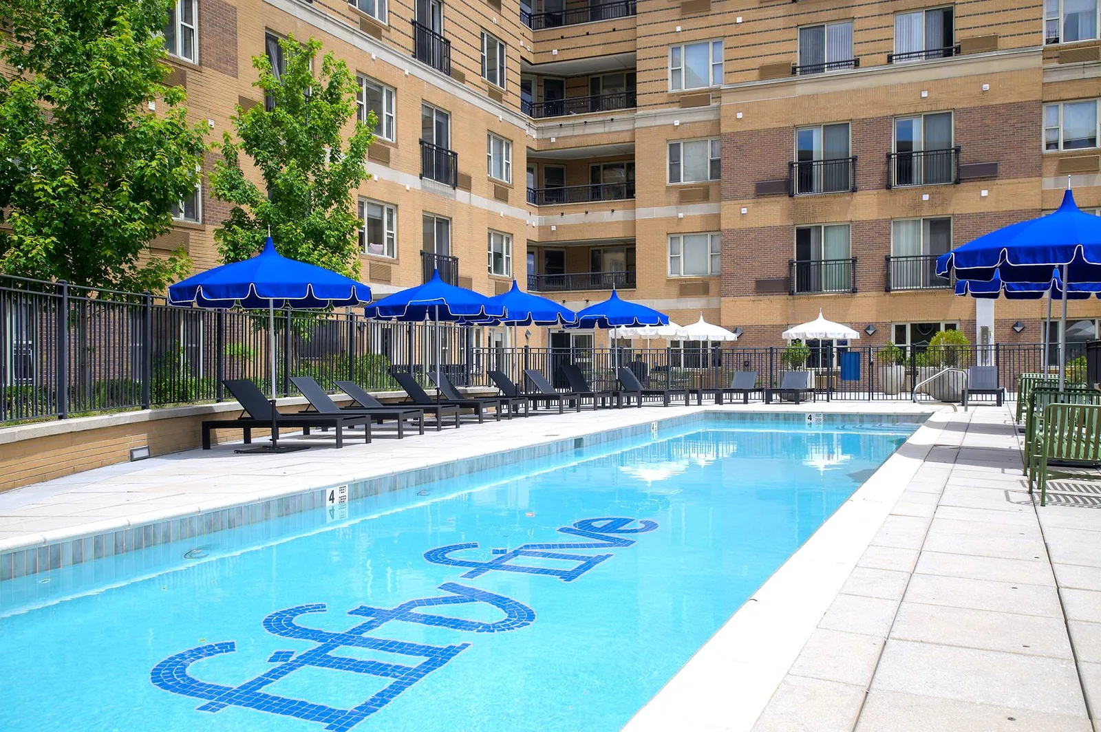 Courtyard pool with blue umbrellas and loungers at an Aker community