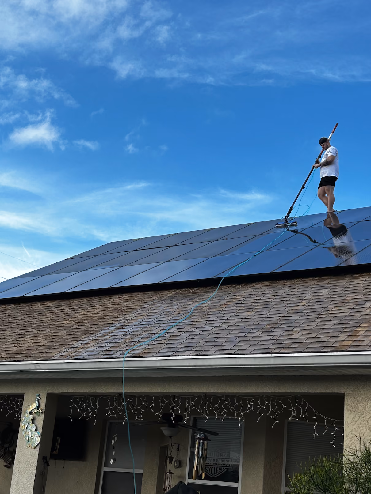 Technician cleaning solar panels on a residential roof in Clearwater