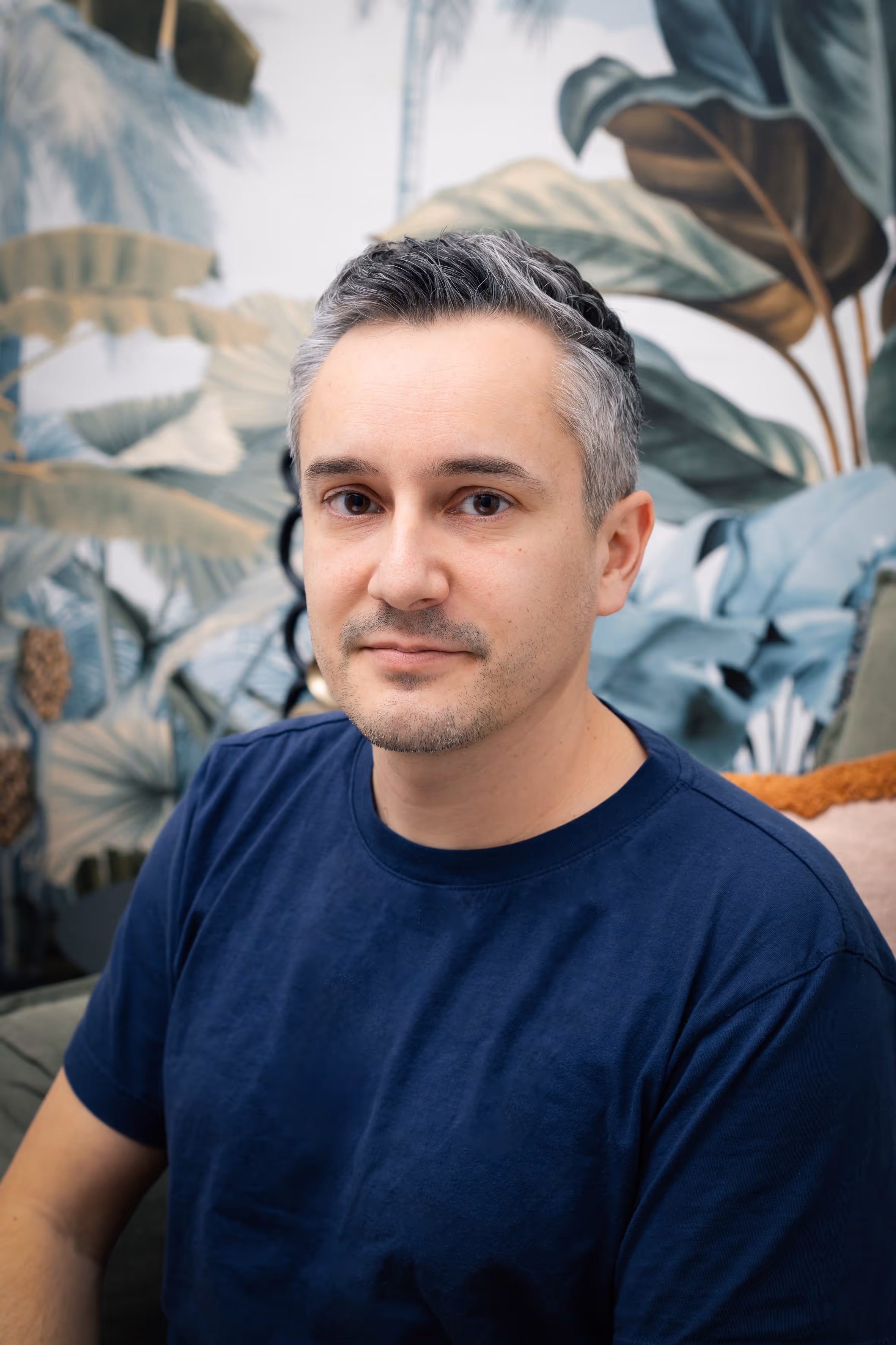 A zoomed in portrait of a man sitting and smiling.