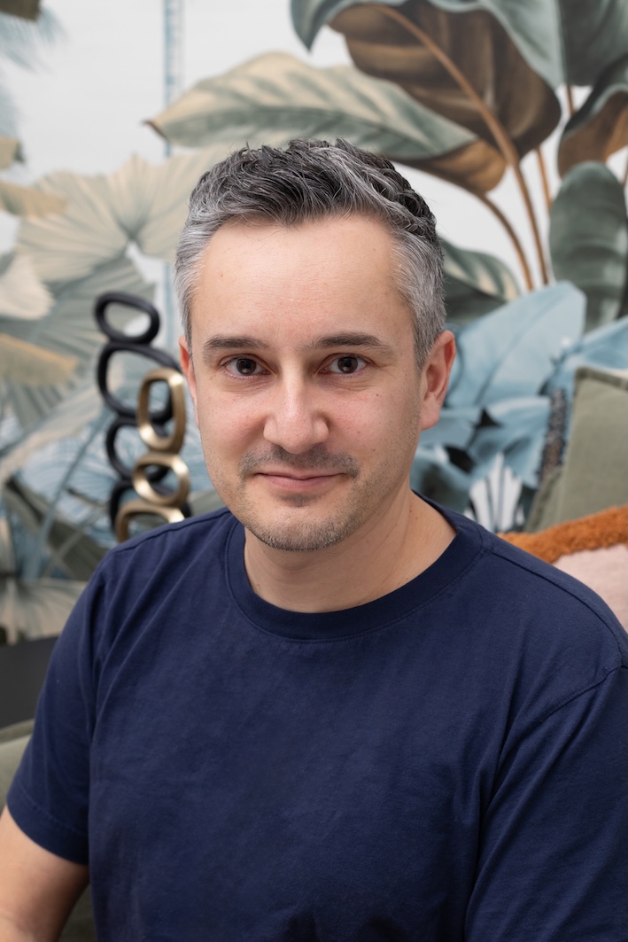 A zoomed in portrait of a man sitting and smiling.