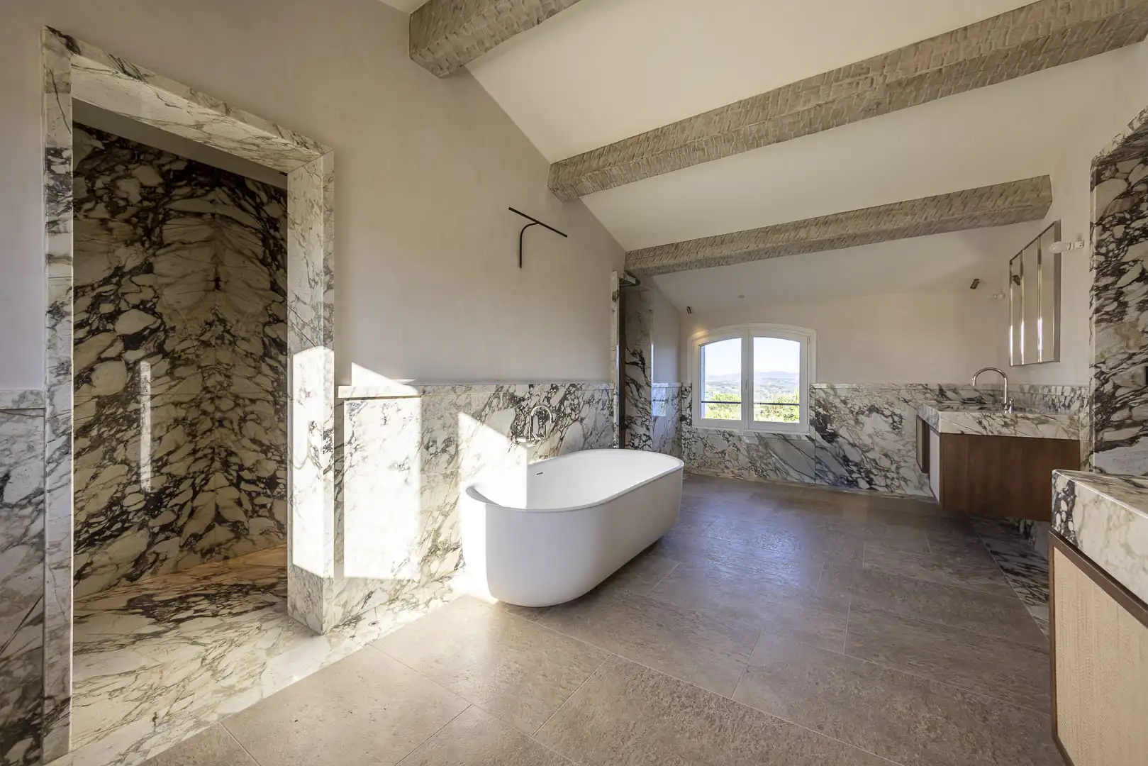 Espace intérieur finalisé avec verrière en menuiserie bois, sol en pierre naturelle et ouverture visuelle vers le paysage.