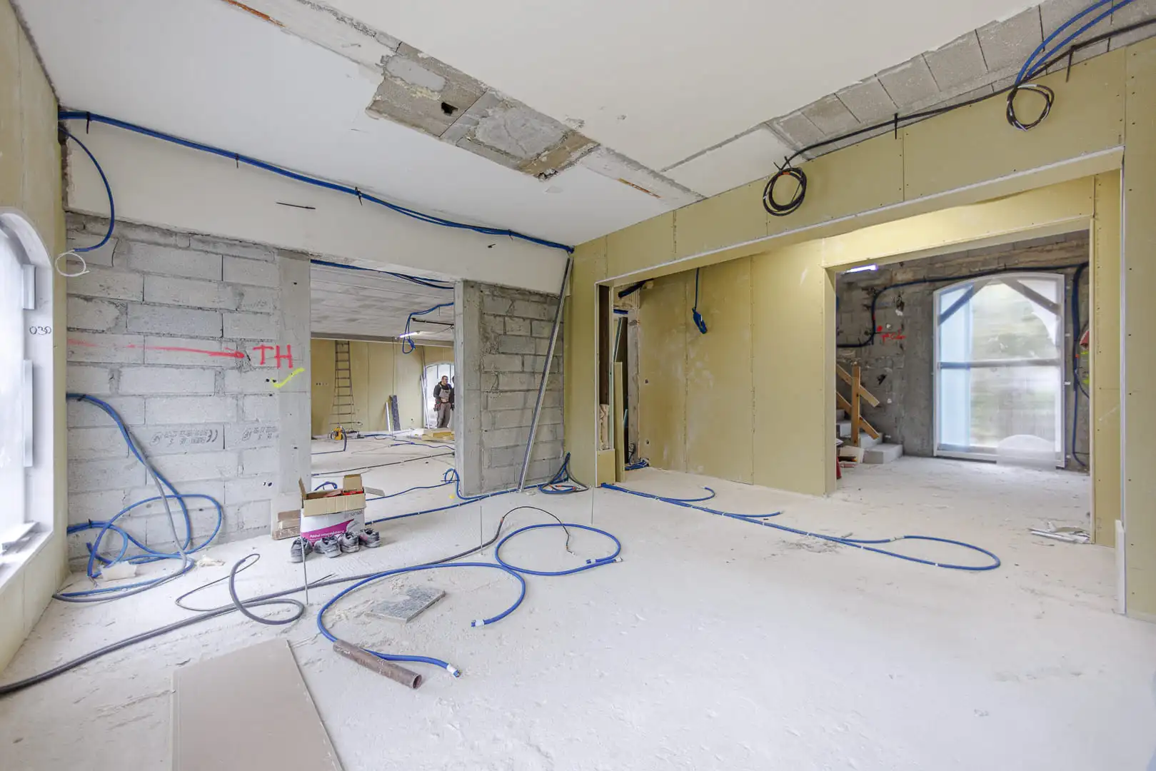 Zone intérieure en phase de second œuvre avec gaines électriques apparentes, création de cloisons et volumes ouverts.