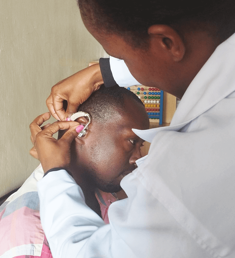 A hearing aid being fitted in a gentleman's ear