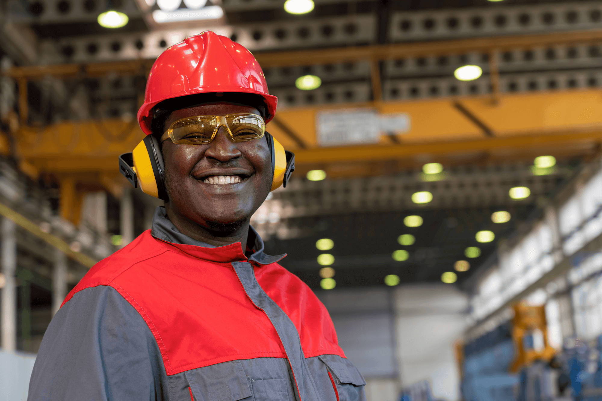 A smiling factory worker waering earmuffs