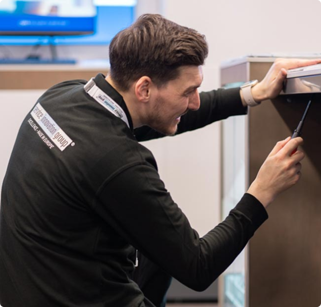 Man using a screwdriver to fix or assemble a piece of furniture or equipment indoors.