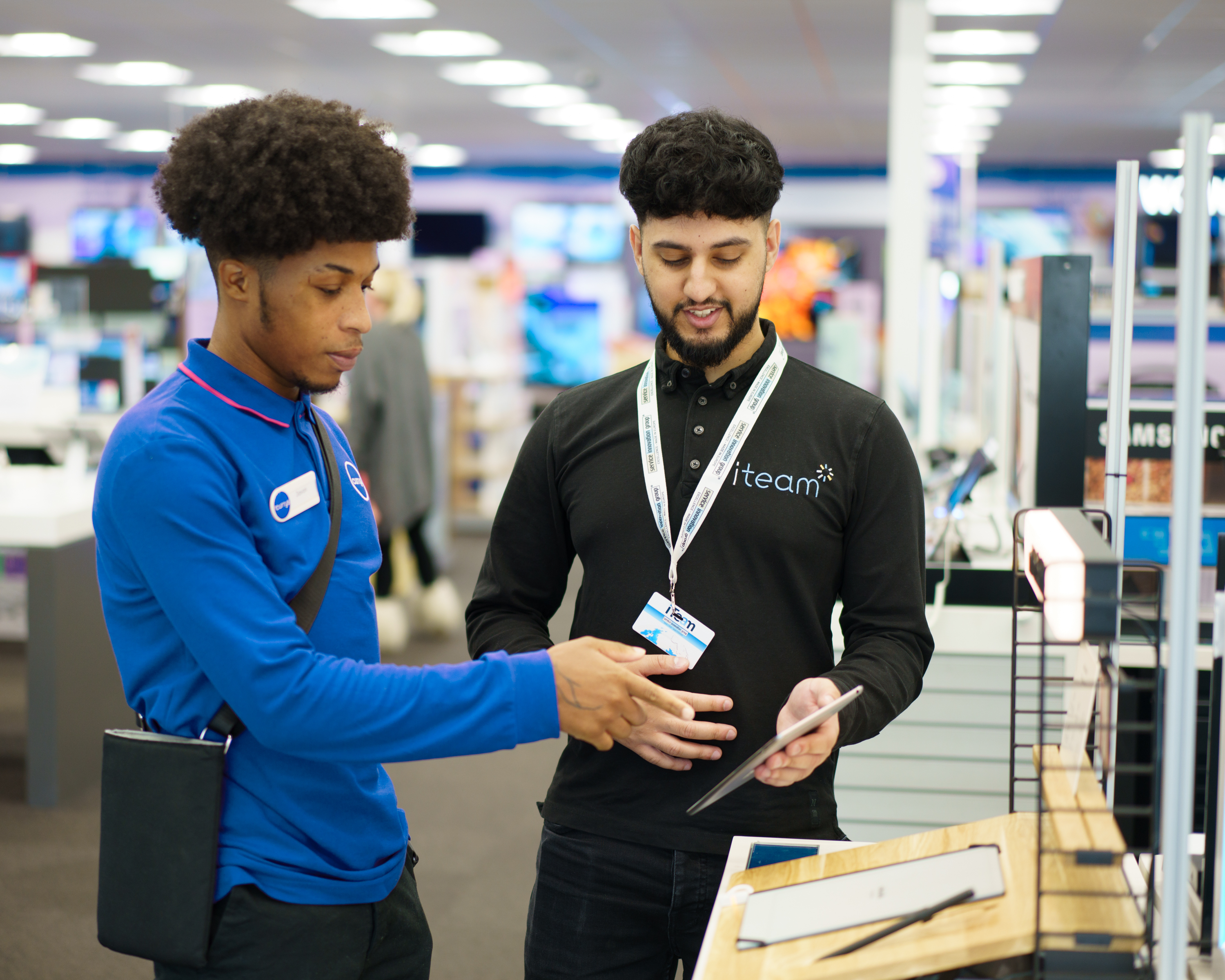 Retail execution specialists reviewing a completed in-store display and quality evidence on a tablet