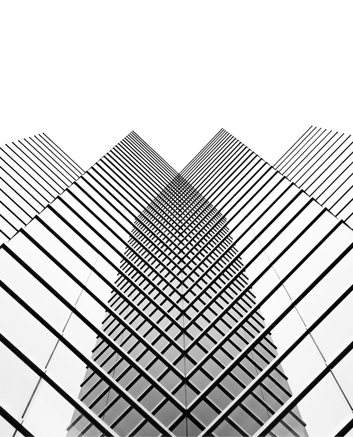 Black and white photo of a modern glass building captured from below, creating a symmetrical, geometric pattern with converging lines and reflections.
