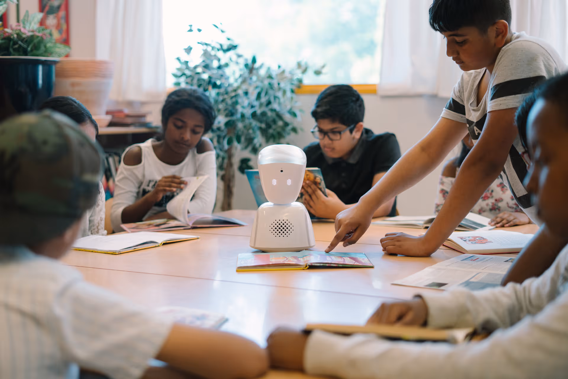 Three girls smiling and holding up an AV1 robot. They are outside in a school playground
