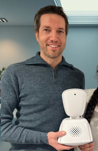 André Sebastiani smiler mens han holder en AV1-robot.