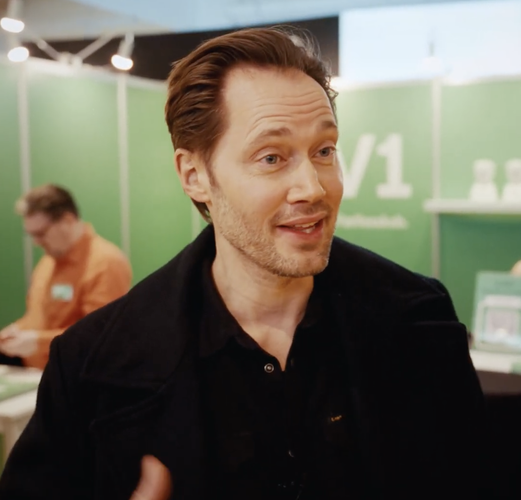 André Sebastiani smiler, mens han holder en AV1-robot.