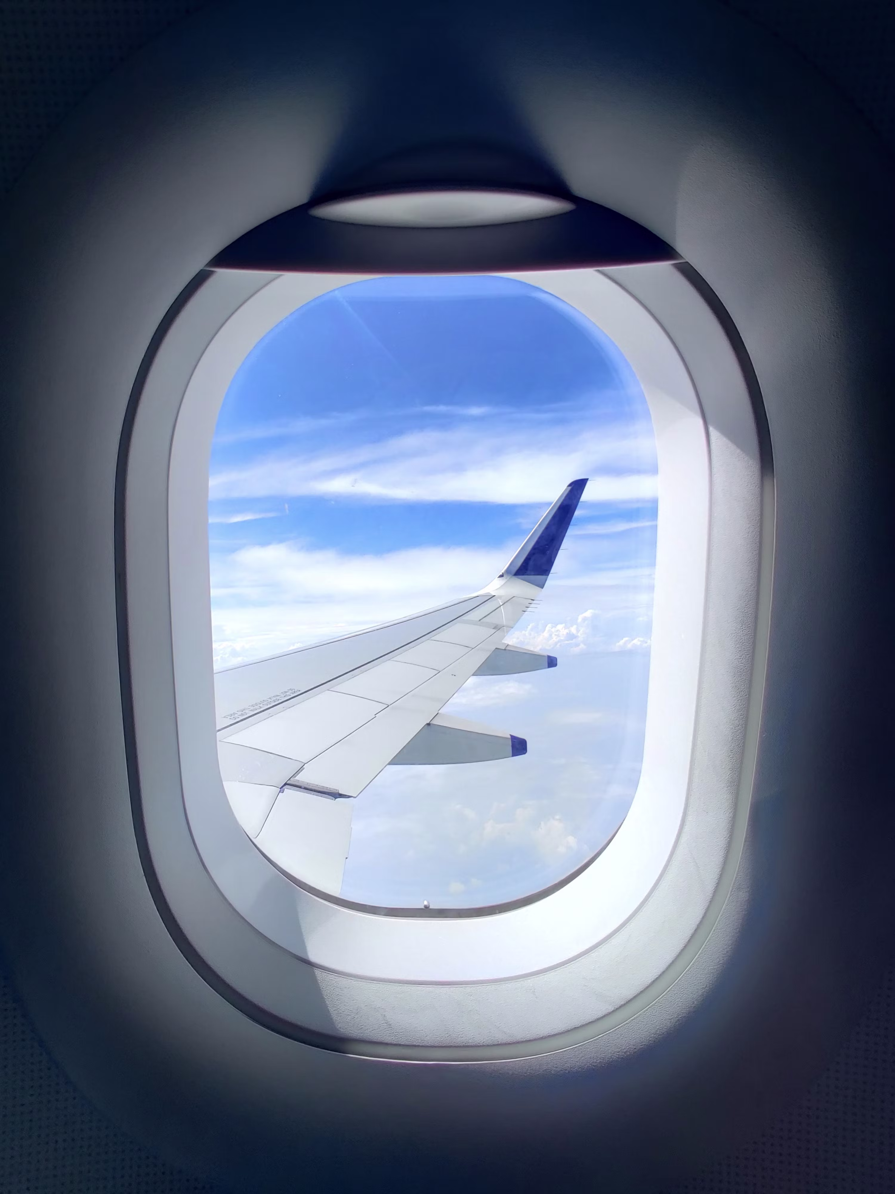 View from air plan window with view of plane wing and blue sky with clouds