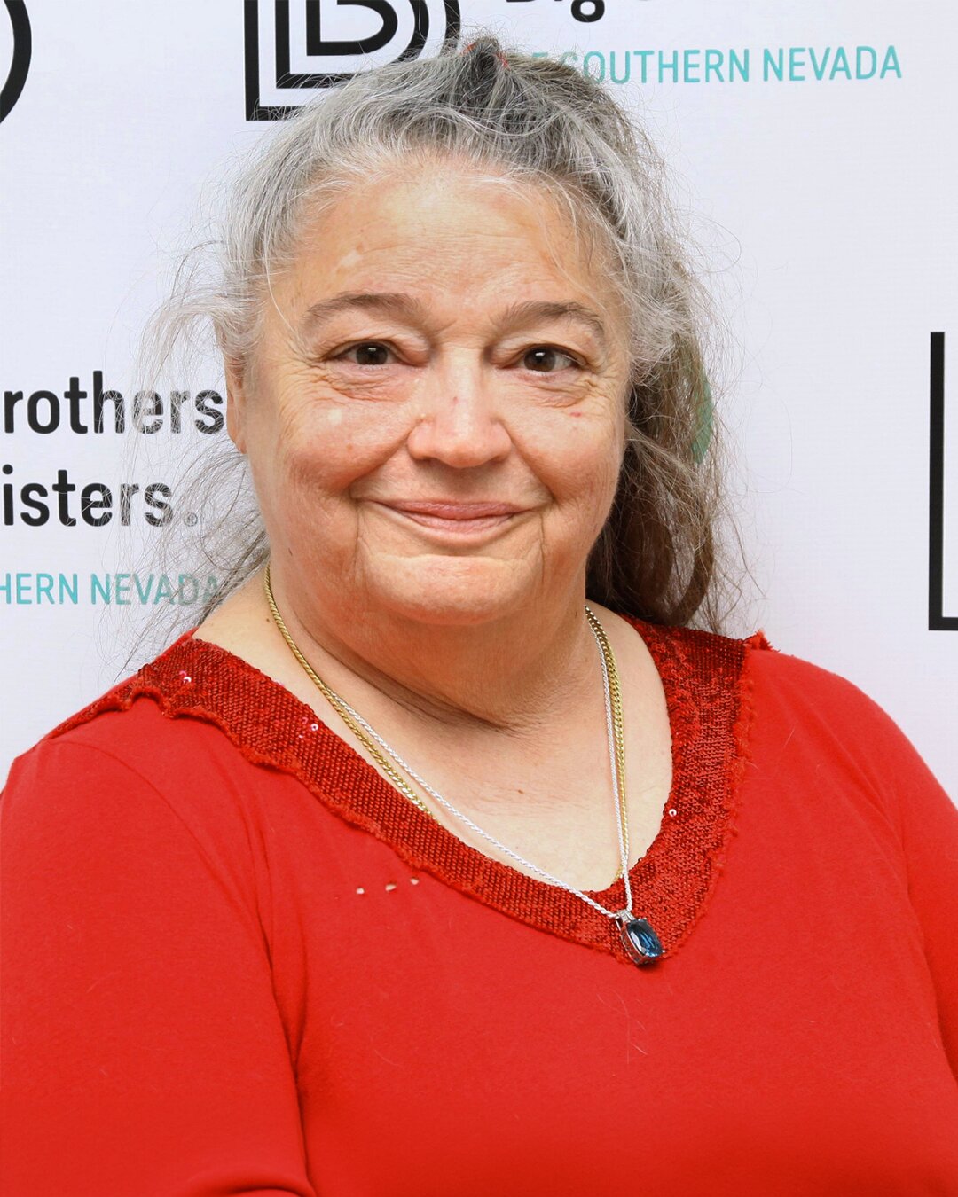 Gloria Sprouse, who works in Donation Center Customer Service, wearing a red shirt and blue necklace