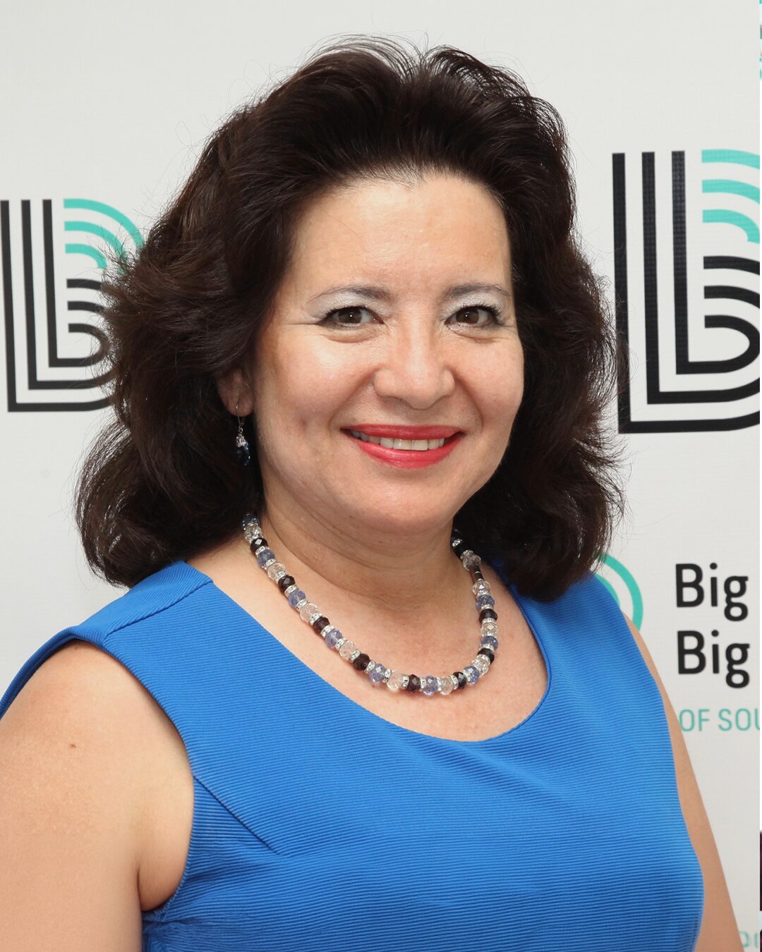 Martha Zacatenco, Program Director, smiling while wearing a blue necklace and tank top