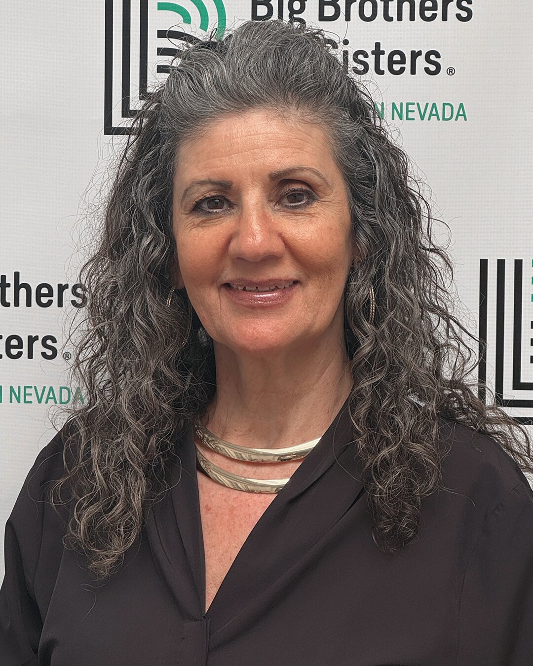 Raquel Maciel, Match Support Specialist, smiling in front of the Big Brothers Big Sisters backdrop