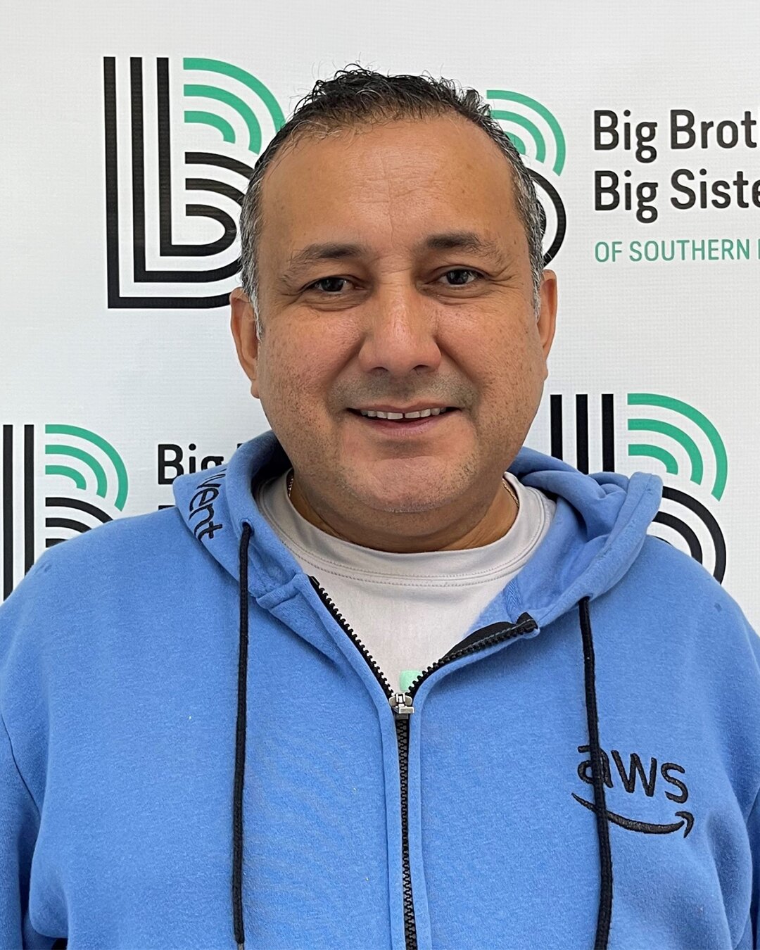Omar Gomez, Donation Center Driver, smiling and wearing a blue hoodie
