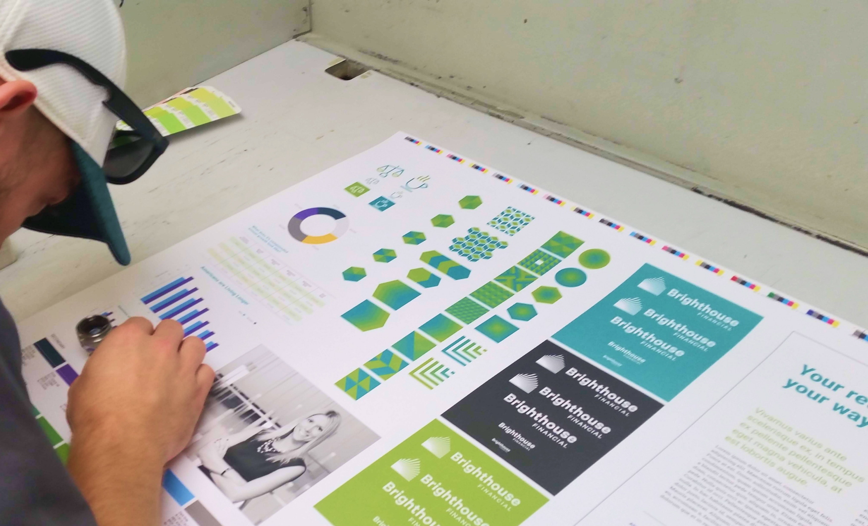 Designer reviewing printed Brighthouse Financial brand materials on a table