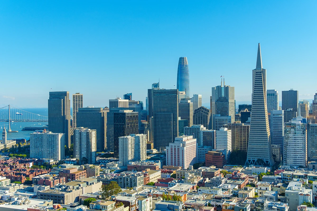 San Francisco skyline with the Transamerica Pyramid and Salesforce Tower under a clear blue sky.