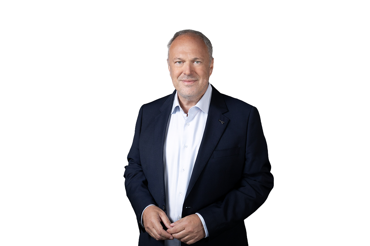 Richard Grasl schaut mit verschränkten Händen in die Kamera.