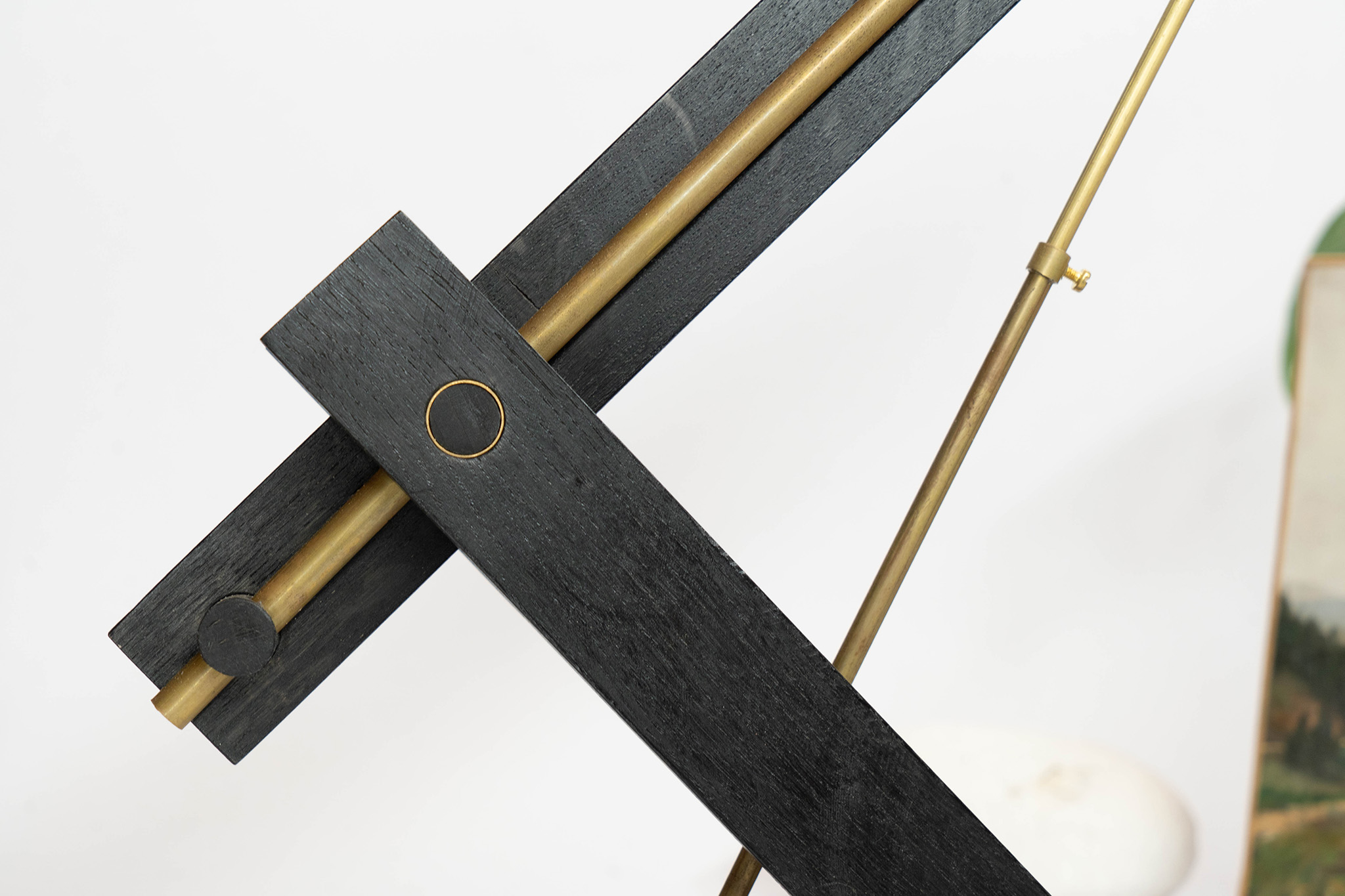 Close-up of a modern adjustable desk lamp with black wooden arms and brass rods against a white background.
