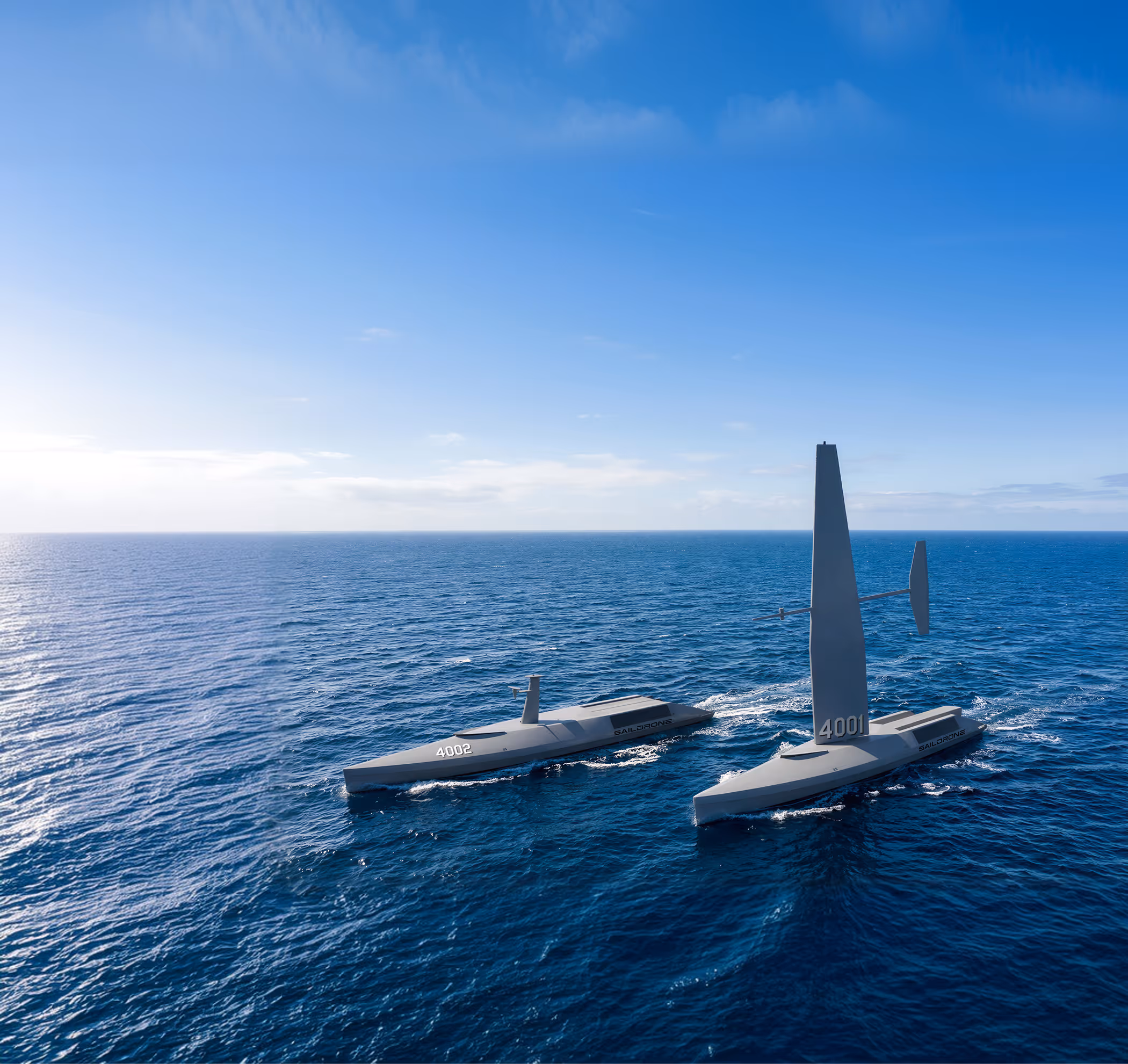 Two autonomous Saildrone vessels labeled 4001 and 4002 sailing on the open ocean under a clear blue sky.