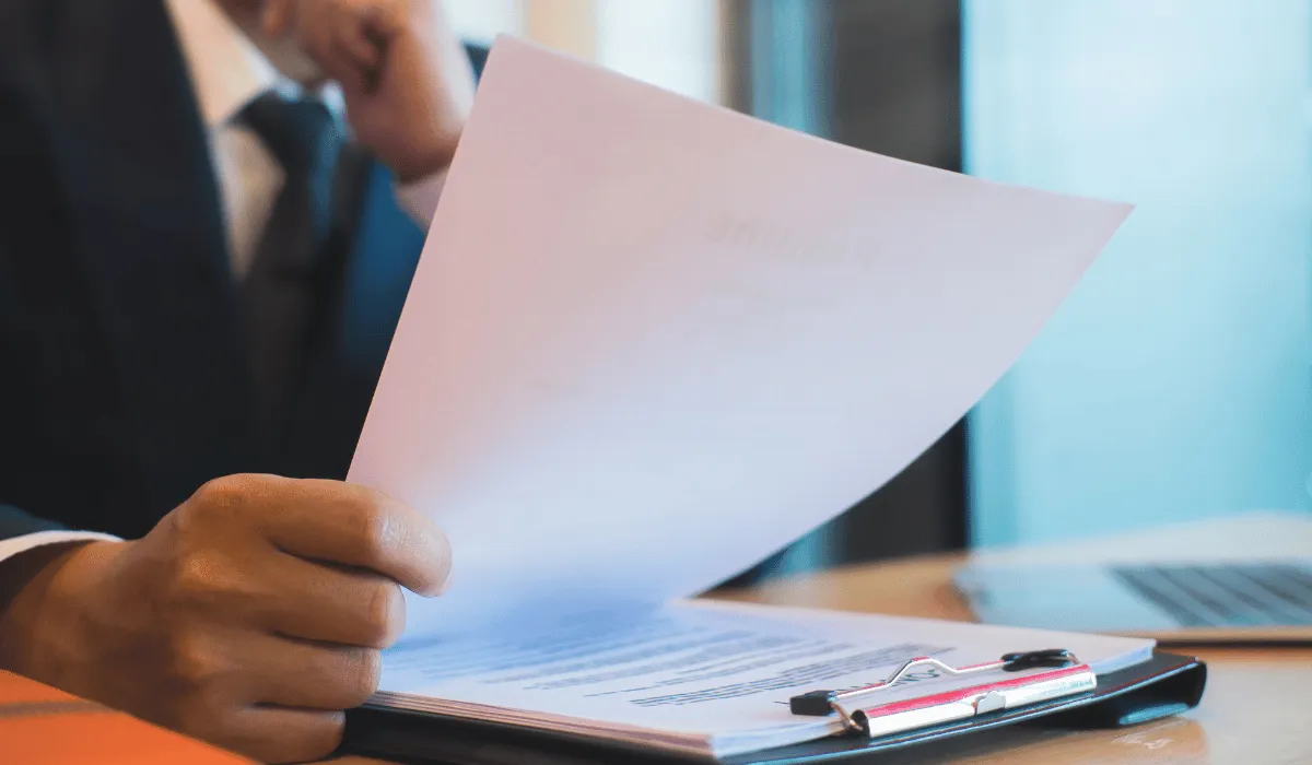 Main d’un homme ramassant un document dans une pile de documents