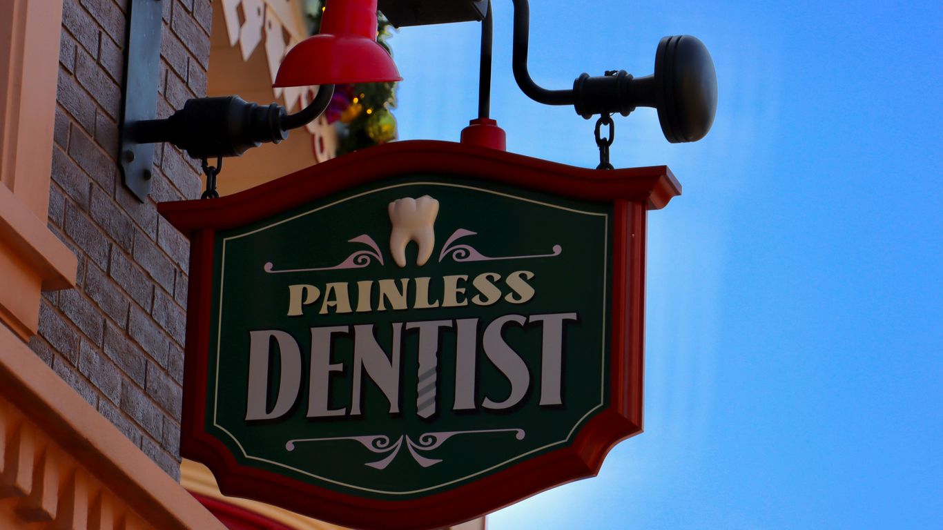 a sign that says painless dentist on the side of a building