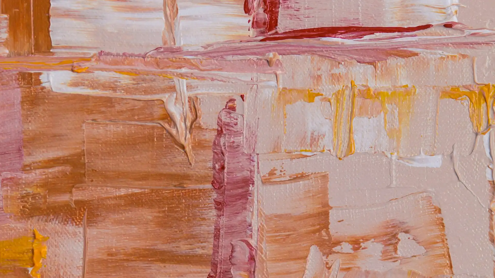 Aerial view of a cityscape at sunset with a long bridge spanning over the sea, vibrant sky colors reflecting on water.