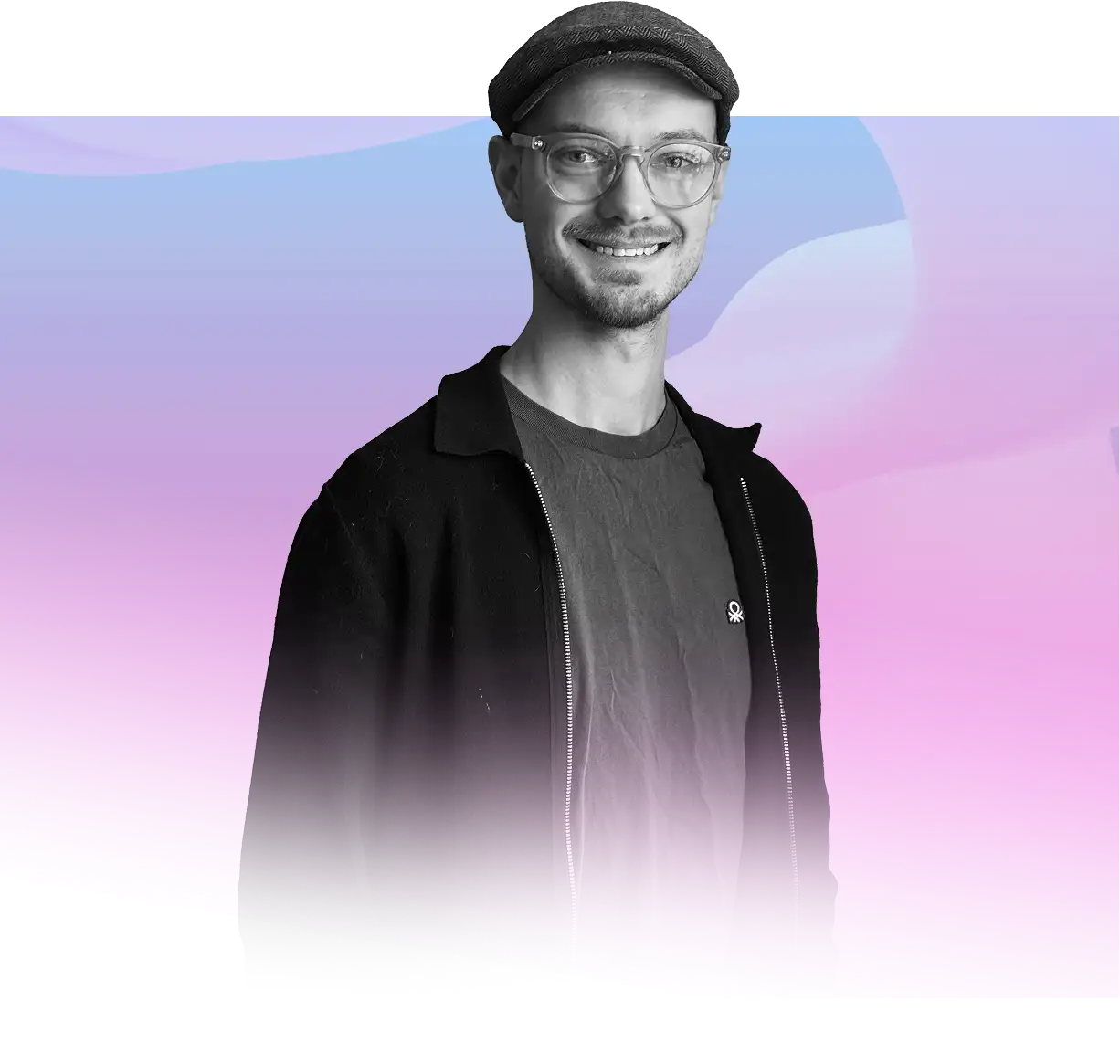 Un homme souriant, portant des lunettes rondes et une casquette plate, vêtu d'une veste noire par-dessus un t-shirt, sur un fond abstrait aux tons violet et bleu pastel.