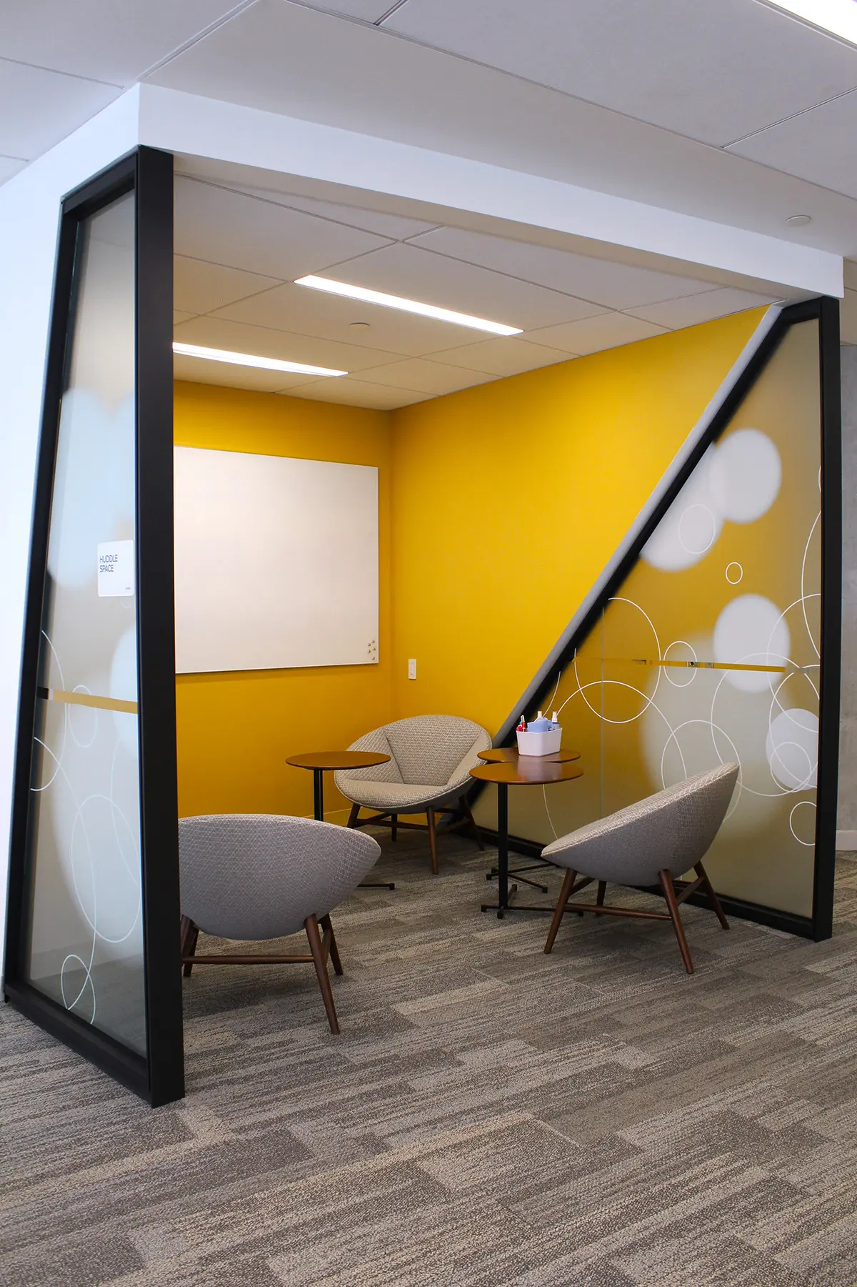 Yellow meeting space with whiteboard, chairs, and moveable glass walls