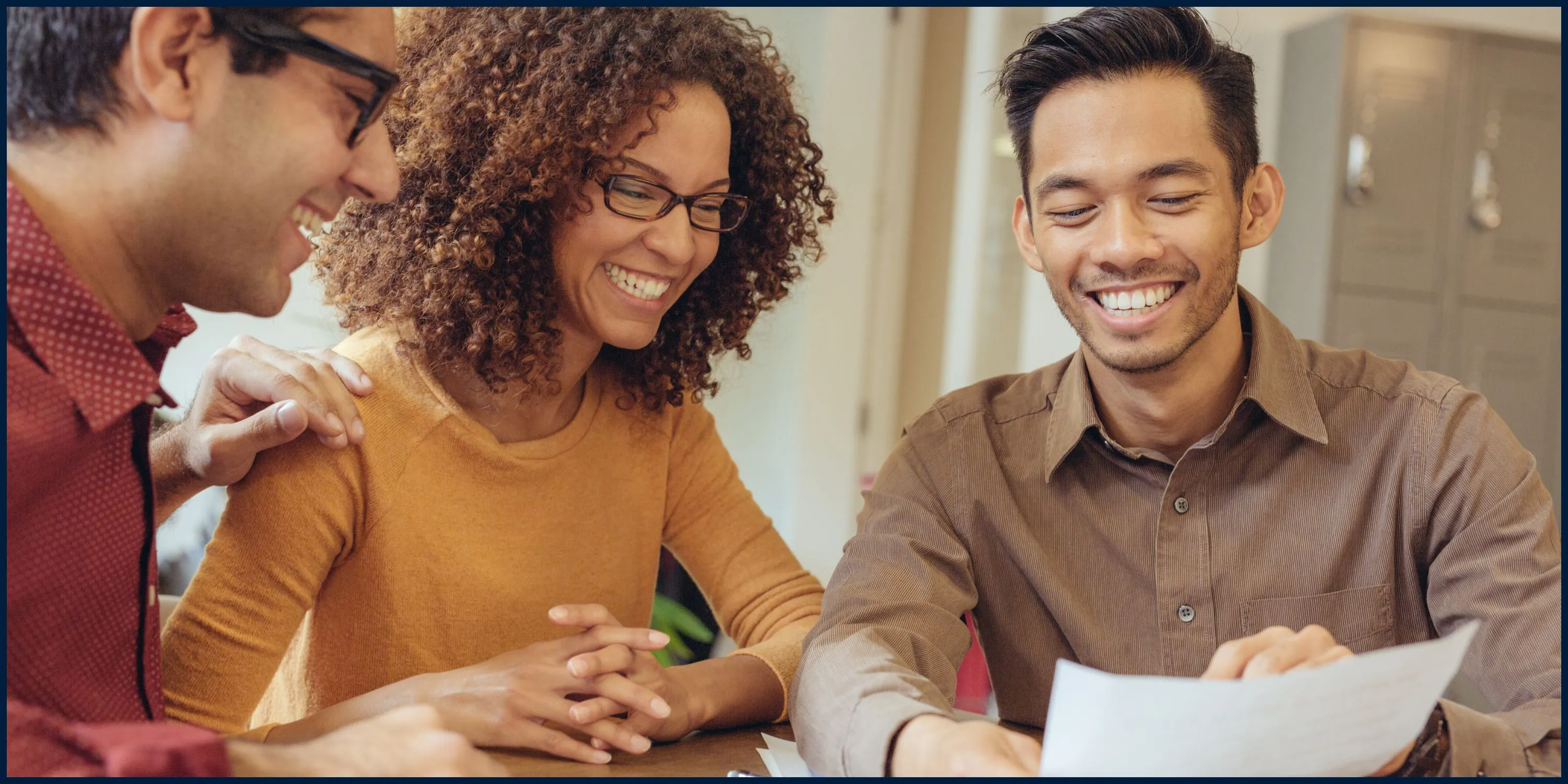 A man and woman sitting at a table smiling and looking at paperwork. - The Fellowship Images