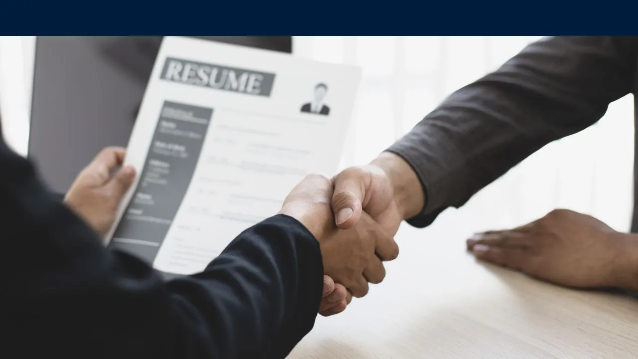 A man shakes another man's hand while holding a resume. - The Fellowship Images