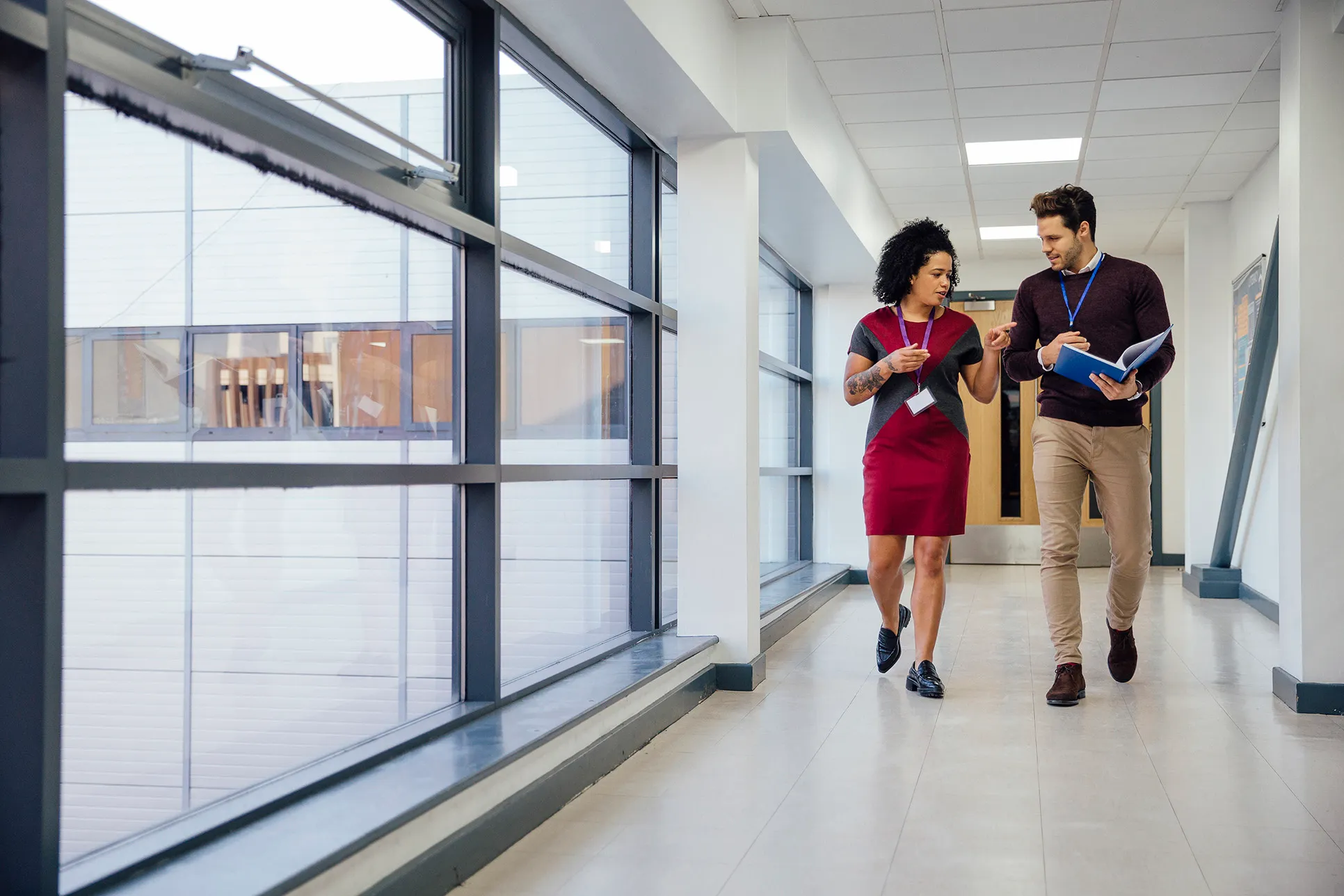 Two people walking and talking in a hallway - The Fellowship Images