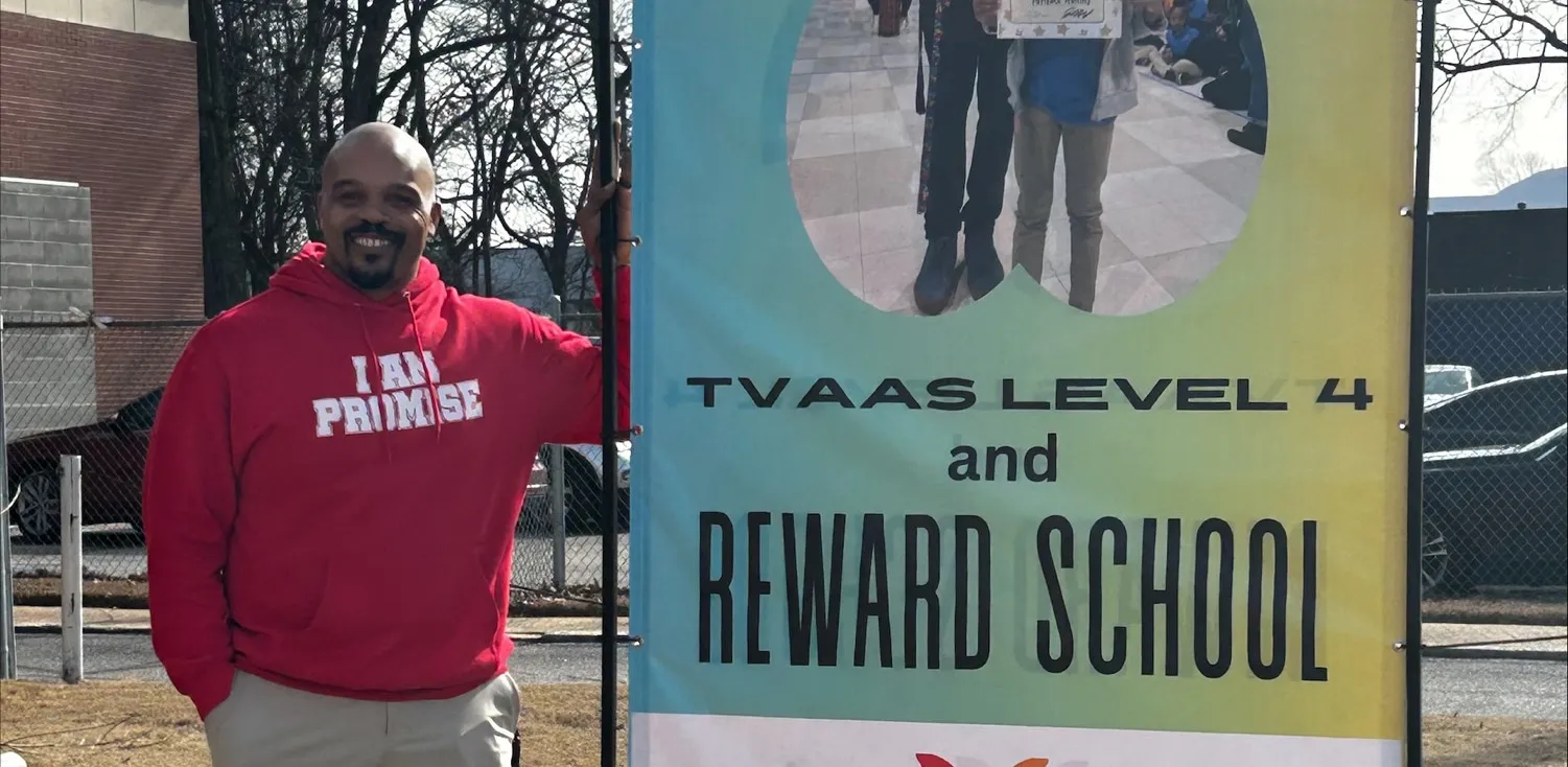 A man in a red sweater standing next to signage - The Fellowship Images