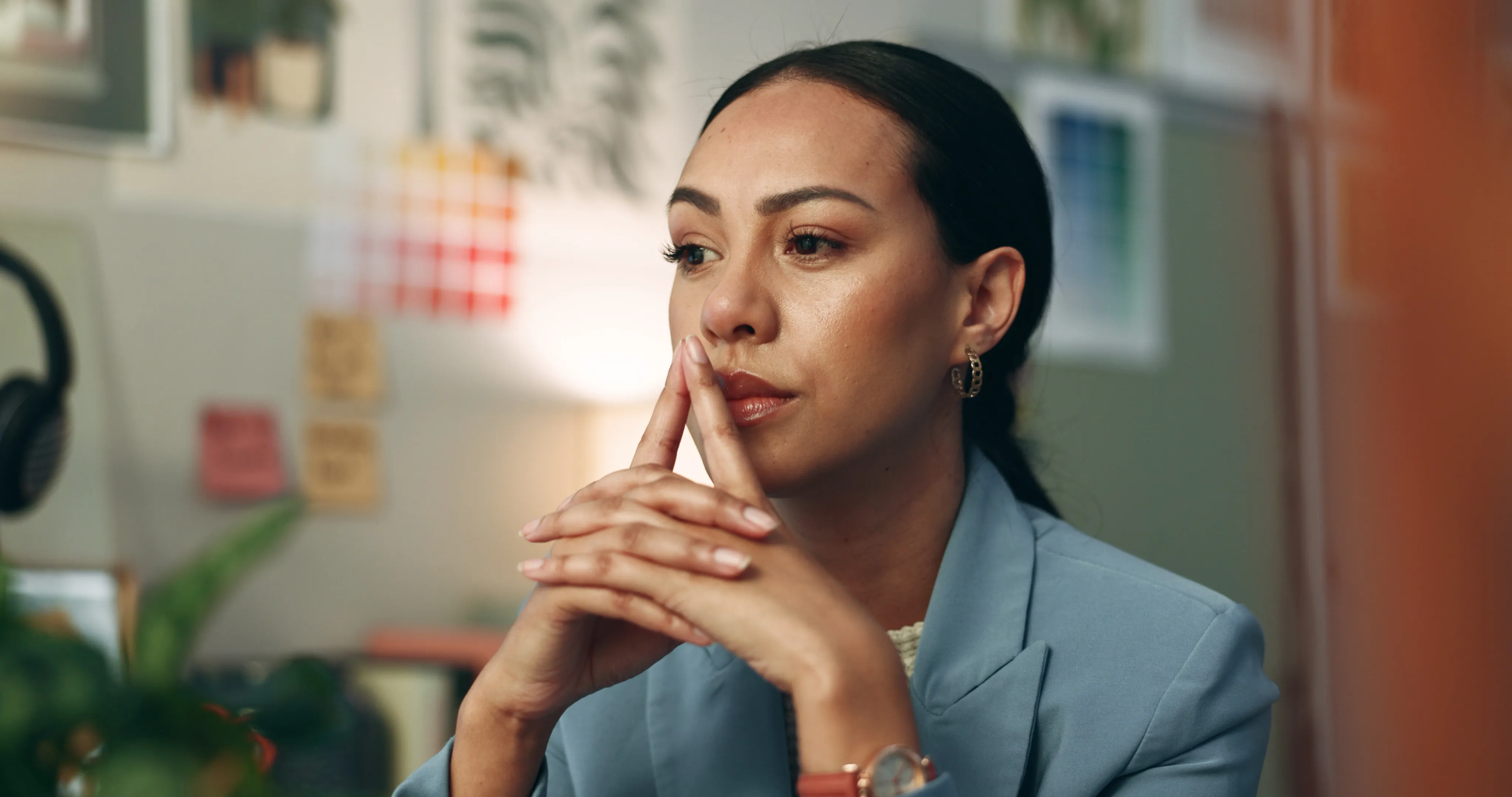 A woman sitting at a desk with her hands up in front of her as in deep in thought - The Fellowship Images