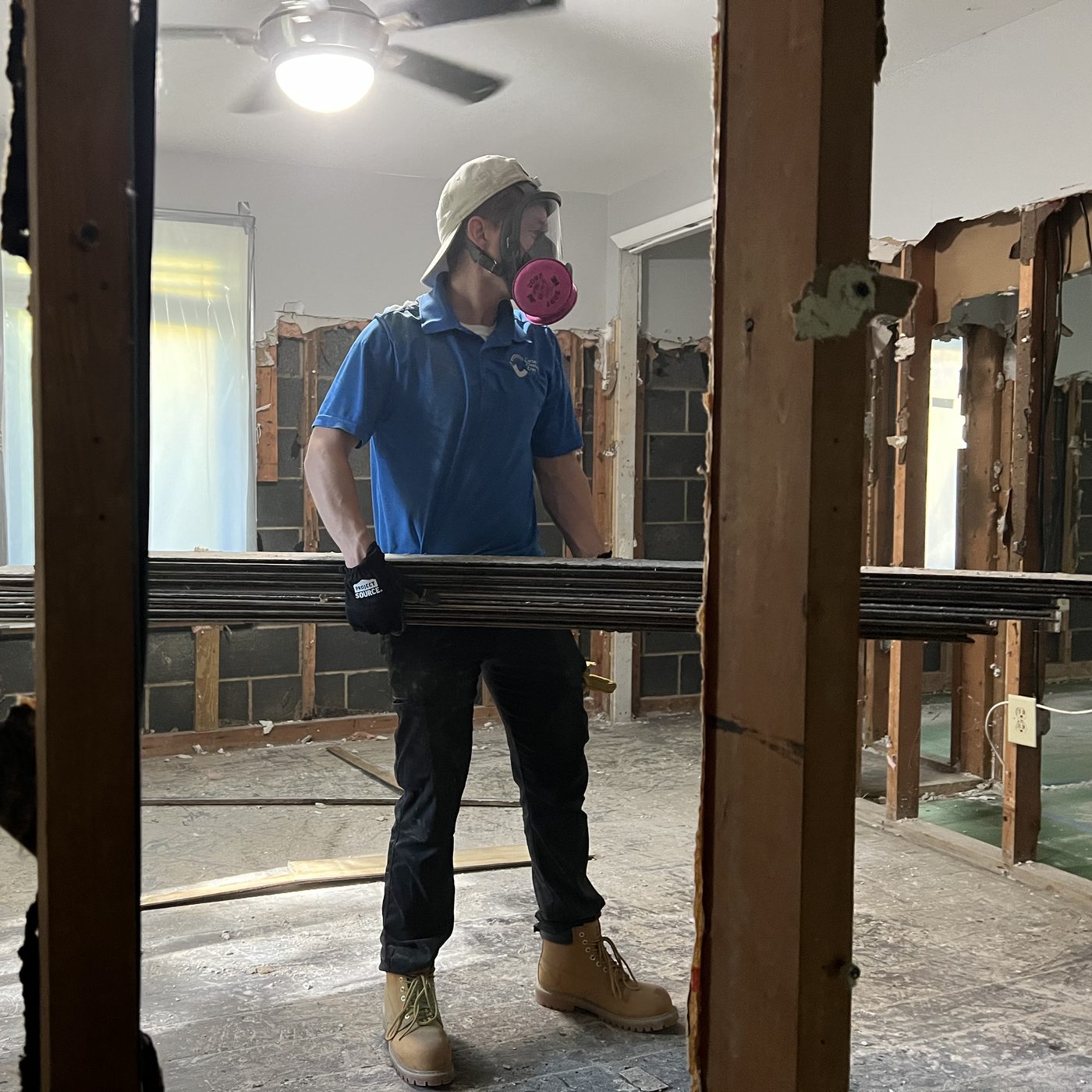 Restoration Crew technician in a respirator carrying out wet flooring after the lower walls were opened up to dry