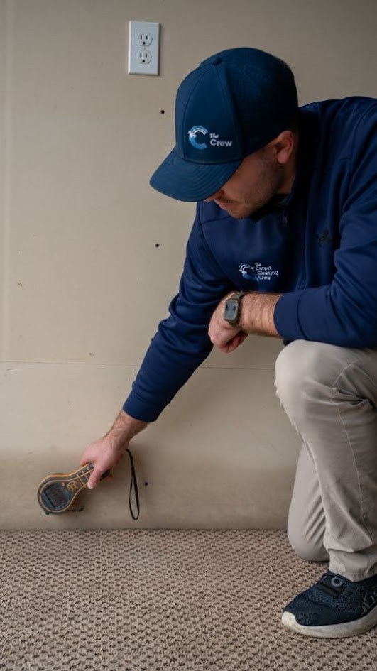 Technician checking the base of a wall with a moisture meter to find hidden water