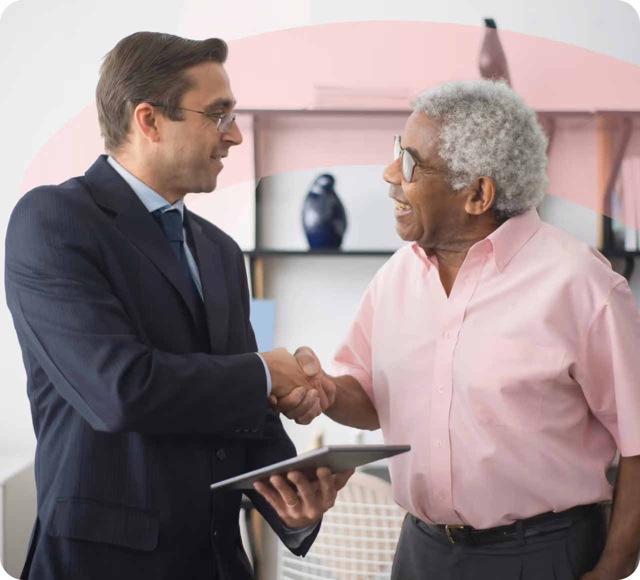 A man in a suit shaking hands with a woman in a pink shirt.