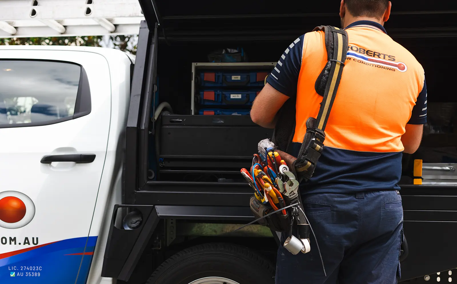 Back of a man getting tools out of a car 