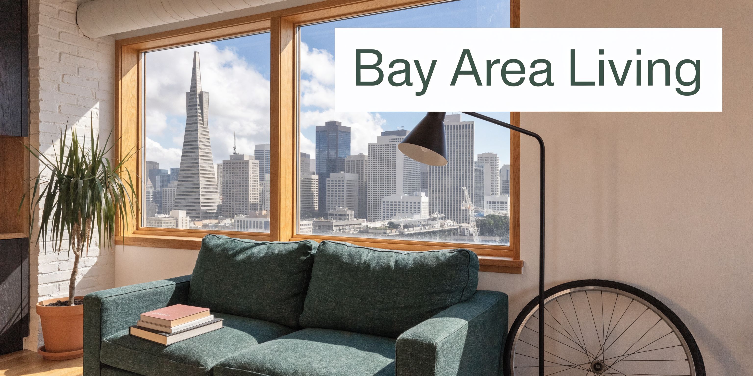 A modern living room with a green sofa and bicycle wheel overlooking the San Francisco city skyline.